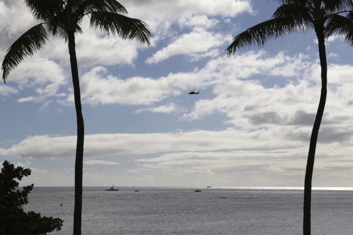 A U.S. Coast Guard helicopter flies over rescue boats at the scene of plane crash off Honolulu, Wednesday, Dec. 12, 2018. Federal Aviation Administration spokesman Ian Gregor said a Hawker Hunter jet went down in the ocean around 2:25 p.m. after taking off from Honolulu’s airport. A civilian contractor for the Hawaii Air National Guard who was participating in a military exercise survived after his plane crashed off the coast of Honolulu, authorities said Wednesday.