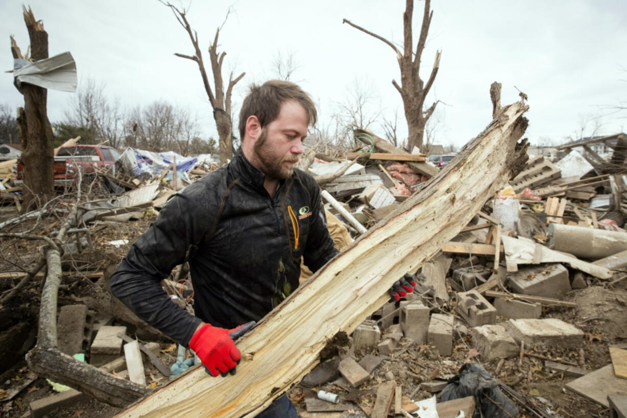 Steven Tirpak cleans debris from the remains of his two-story home Sunday in Taylorville, Ill.