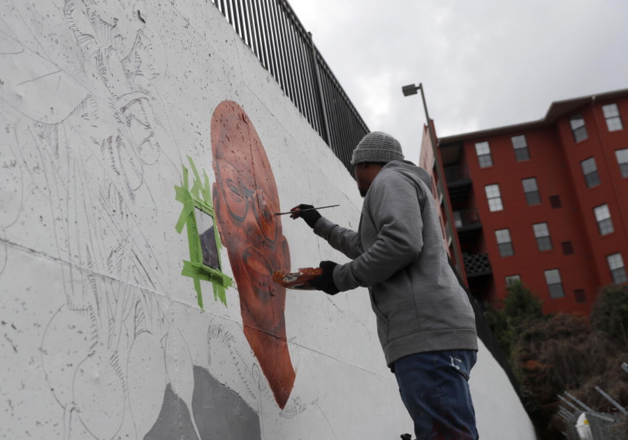 Muhammad Yungai paints mural on a building near the Mercedes Benz Stadium in Atlanta. A series of about 30 murals on walls around the downtown Atlanta stadium that will host the Super Bowl aims to highlight Atlanta’s civil rights legacy.