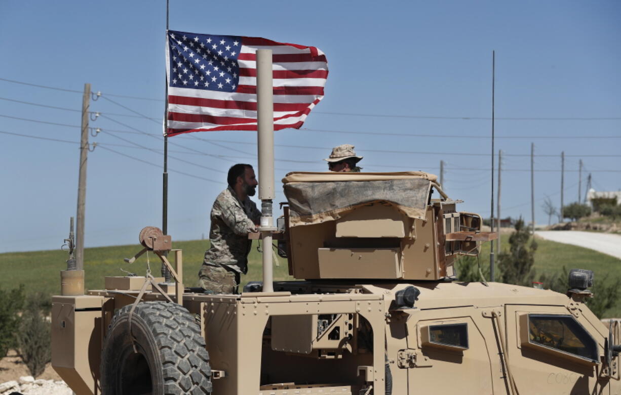 A U.S-backed Syrian Manbij Military Council soldier, left, speaks with a U.S. soldier, at a U.S. position near the tense front line with Turkish-backed fighters, in Manbij town, north Syria, in April. President Donald Trump’s decision to withdraw troops from Syria has rattled Washington’s Kurdish allies, who are its most reliable partner in Syria and among the most effective ground forces battling the Islamic State group. Kurds in northern Syria said commanders and fighters met into the night, discussing their response to the surprise announcement Wednesday, Dec. 20, 2018.