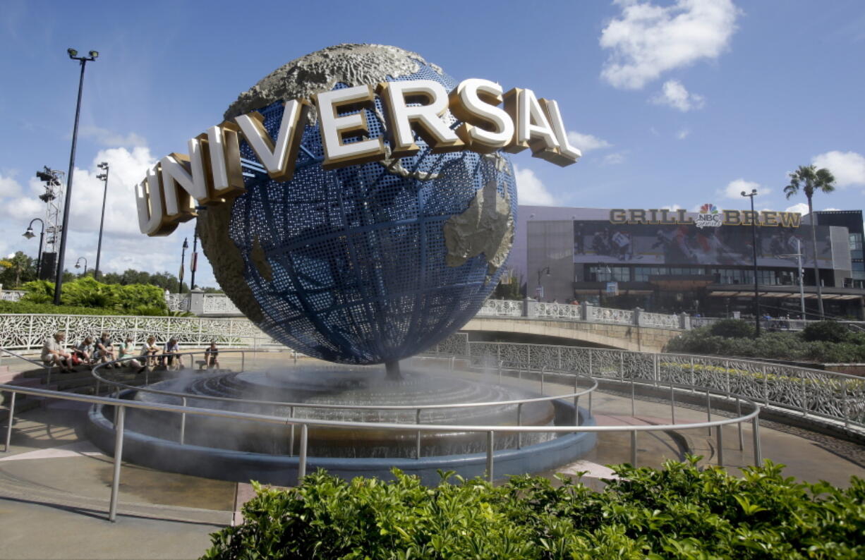 FILE- In this Oct. 22, 2015 file photo, park guests relax and cool off with a water mist under the globe at Universal Studios City Walk in Orlando, Fla. A lawsuit brought by a Guatemalan family whose father died after going on a ride says Universal Orlando Resort should have put warning signs in Spanish.