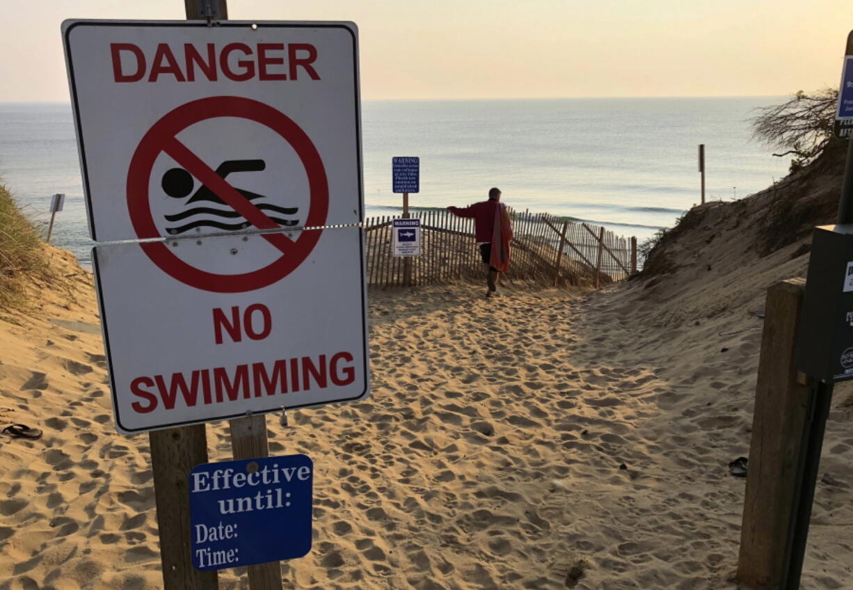 FILE - in this Aug. 16, 2018 file photo, Steve McFadden, of Plattsburgh, N.Y., gazes at Long Nook Beach in Truro, Mass. Authorities closed the beach to swimmers after a man was attacked there by a shark the previous day. Cape Cod is trying to determine ways to respond to the Truro attack, and to a Sept. 15 shark attack in nearby Wellfleet where a 26-year-old man was badly injured and later died at a hospital. It was the state’s first shark attack fatality in more than 80 years. (AP Photo/William J.