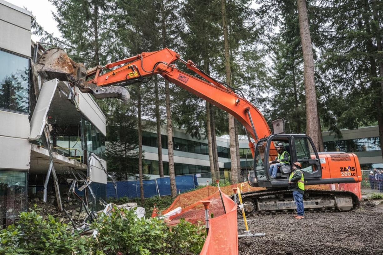 Matthew Whilden, a Microsoft senior software engineer, operates an excavator under the watchful eye of PCI Democon supervisor Gordon Bowman during building demolition that is part of the modernization of Microsoft’s Redmond campus.