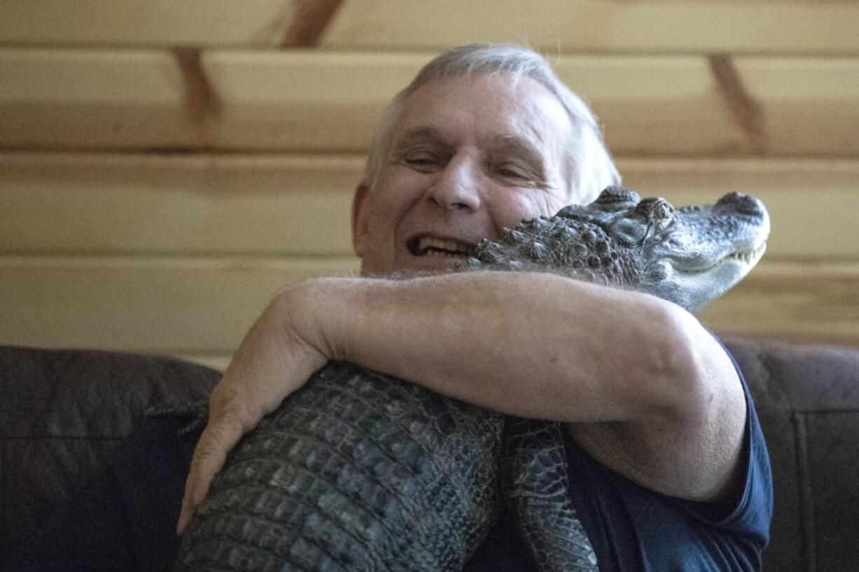 Joie Henney, 65, hugs his emotional support alligator, Wally, inside his home in York Haven, Pa.