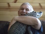 Joie Henney, 65, hugs his emotional support alligator, Wally, inside his home in York Haven, Pa.