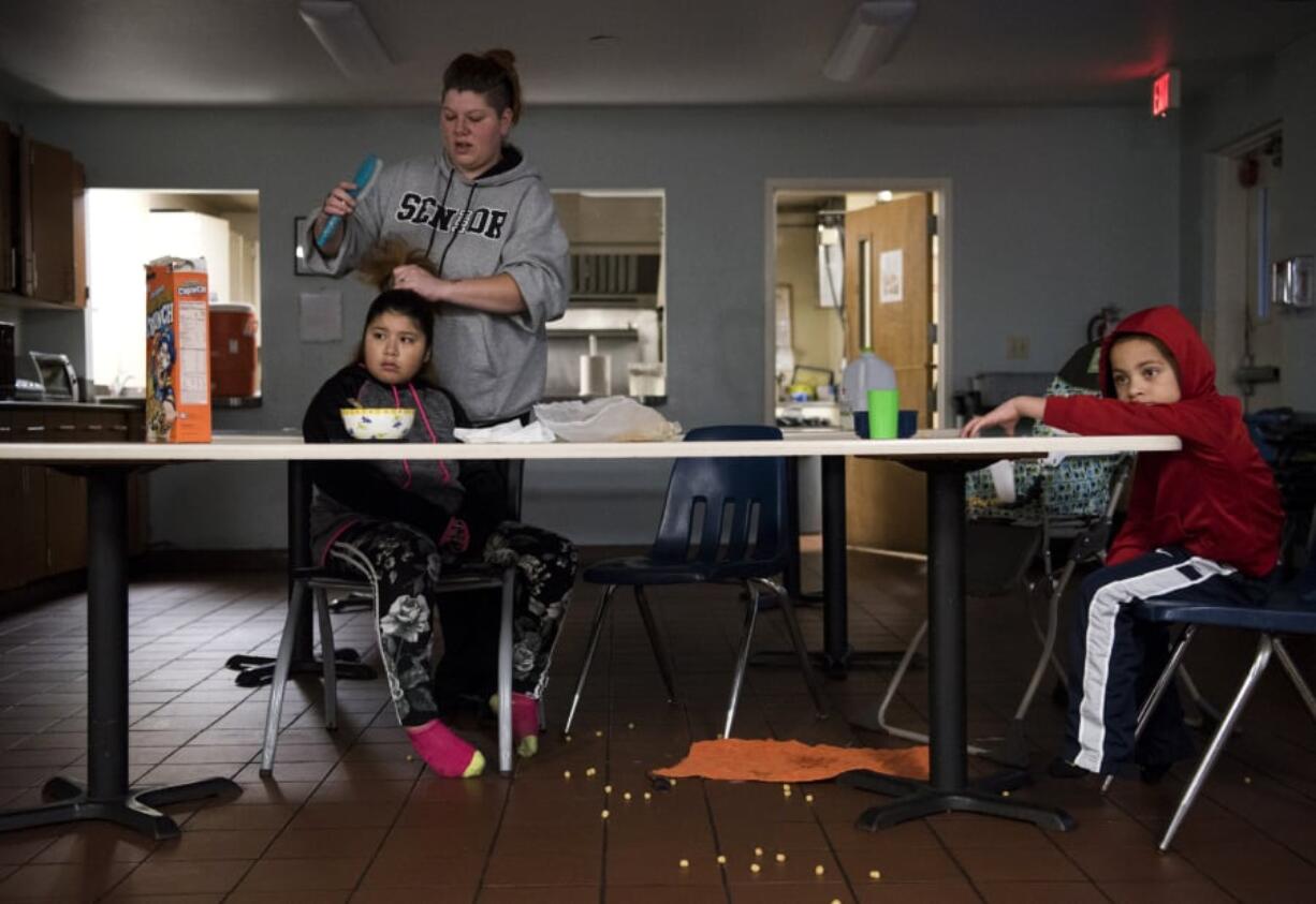 Paige Magana helps her daughter Alexia Bautista-Matias-Cannon, 11, get ready for school as Alexia and her brother Antwone Richardson Jr., 5, eat breakfast in Share Homestead’s common area Dec. 12. The shelter sets out snacks for the kids to eat before breakfast, but some families buy their own cereal and breakfast foods.