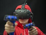 Ricky Watkins of Illinois takes aim while playing the zombie shooter VR game “Arizona Sunshine” at VR Junkies in Vancouver Mall. The game is one of the most popular titles at the arcade, in part because it allows cooperative play for multiple visitors.