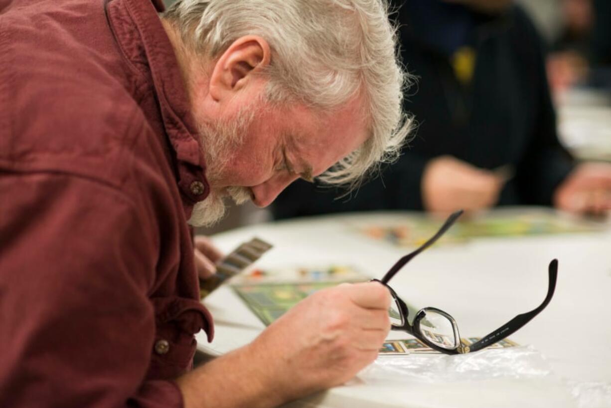 Gamer Glenn Johnson studies his cards while playing the board game Glass Road.