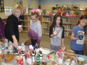 Washougal: Washougal Superintendent Mary Templeton, from left, helps students Madison Reaves, Hannah Hassing and Tessandra Townsend look for presents at Hathaway Elementary School’s gift store.