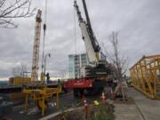 Construction workers unload pieces for assembly as they build the tower crane, left, that will be used to build the Hotel Indigo and Kirkland Tower at the Vancouver Waterfront.