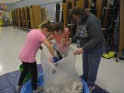 Washougal: Gause Elementary School students Parker Forsberg and Kamea Roy, from left, help Ellen Lancaster, Gause Day custodian and Green Team adviser, remove items mistakenly sorted in with milk cartons.