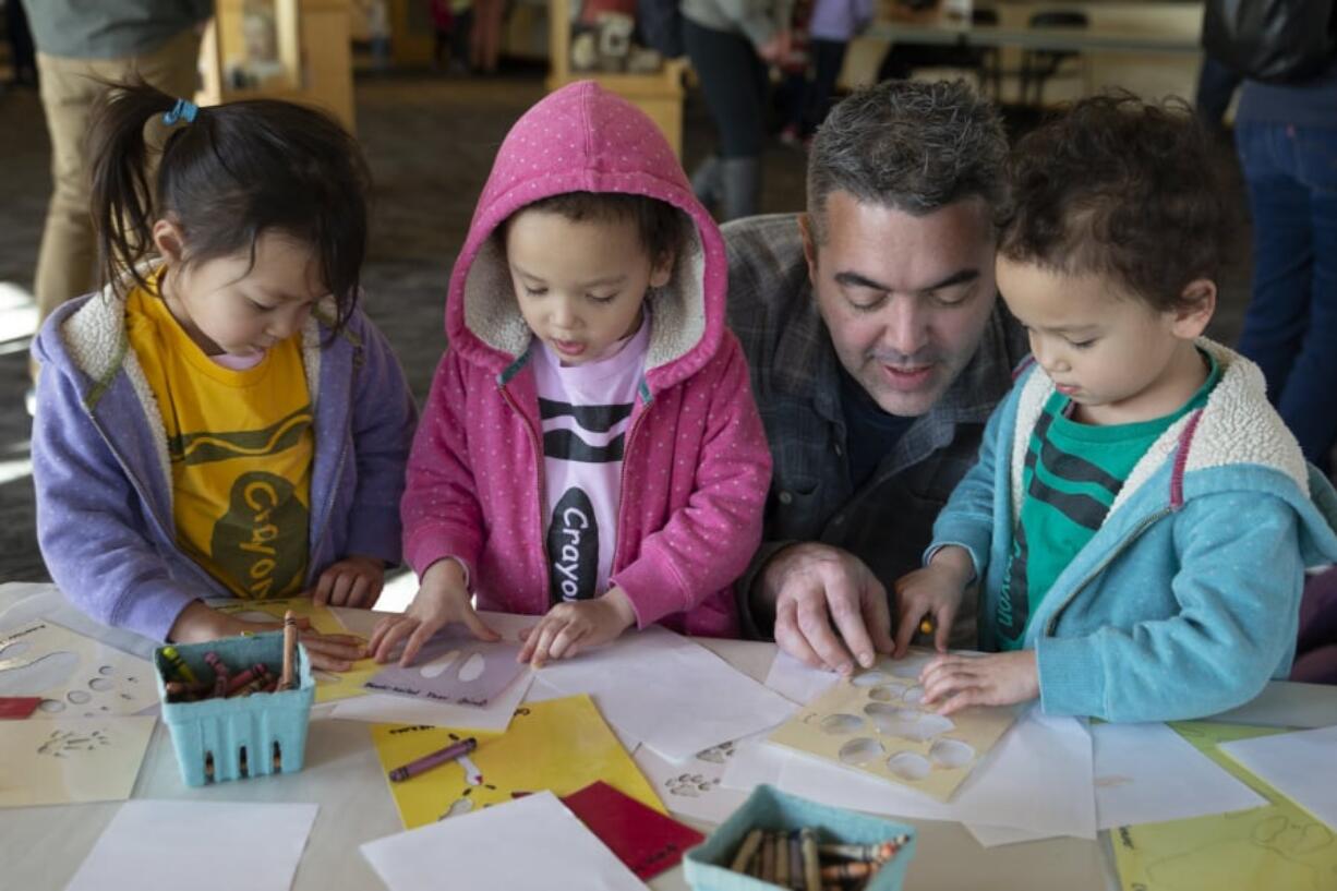 Dan Clayton, second from right, helps his triplet 4-year-old daughters make animal footprints during interactive activities at the Second Saturday “Mammals of the Columbia” event at Vancouver’s Water Resources Education Center on Saturday. From left to right are Amelia, Fiona and Madeline. The family is from Camas. At top: Henry Grice, 5, walks like a deer at the Second Saturday “Mammals of the Columbia” event at Vancouver’s Water Resources Education Center on Saturday. Henry was accompanied by his dad, Corey. They are from Portland. (Randy L.