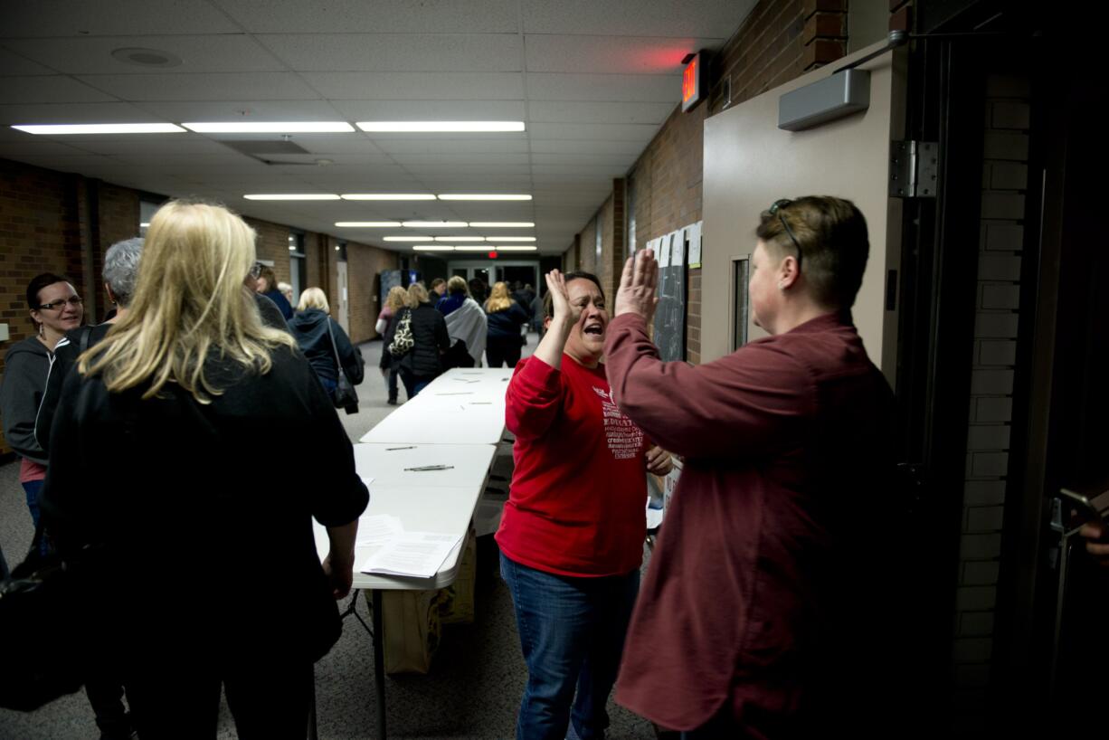 Members of the Vancouver Association of Educational Support Professionals voted Friday to ratify a three-year contract with Vancouver Public Schools. Yvette De La Cruz, center, Washington Education Association staff, shares high-fives as members leave the meeting.