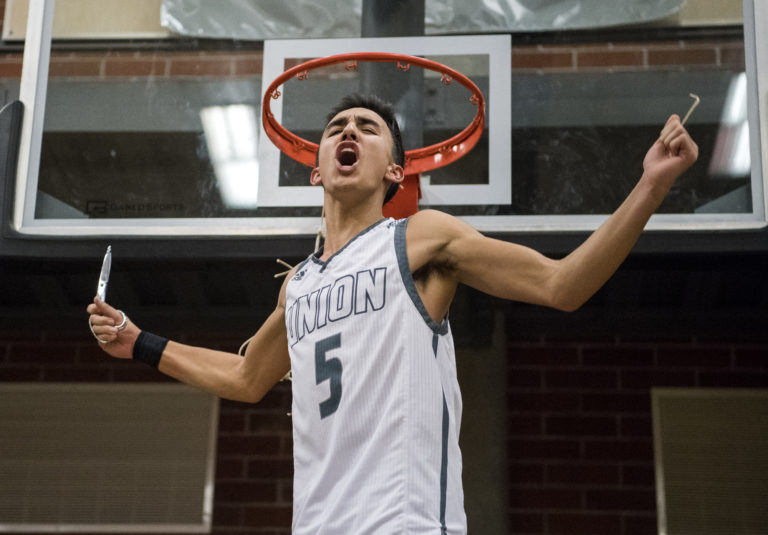 Union's Houston Combs (5) cuts a piece of the basketball net after defeating Skyview in Wednesday night's game and securing the 4A Greater St. Helens League title at Union High School on Jan. 30, 2019. Union won 72-55.