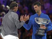 Serbia's Novak Djokovic, right, shakes hands with Spain's Rafael Nadal on the podium after winning the men's singles final at the Australian Open tennis championships in Melbourne, Australia, Sunday, Jan. 27, 2019.