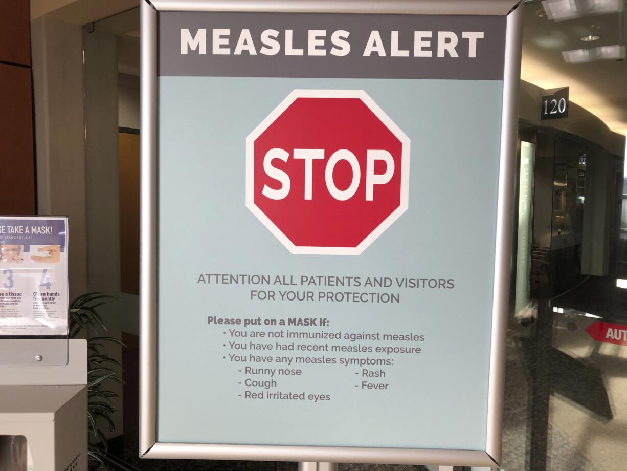 Signs posted at The Vancouver Clinic in Vancouver, Wash., warn patients and visitors of a measles outbreak on Wednesday, Jan. 30, 2019. The outbreak has sickened 39 people in the Pacific Northwest, with 13 more cases suspected. At least one patient who was sick with the measles has come to this clinic for treatment since the outbreak began Jan. 1, 2019.