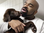 In this Jan. 8, 2019, photo, inmate Jonathan Ladson cuddles with a chocolate lab puppy at Merrimack County Jail in Boscawen, N.H. The New Hampshire jail is the first in the state to partner prisoners with the “Hero Pups” program to foster and train puppies with the goal of placing them with military veterans and first responders in need of support dogs.