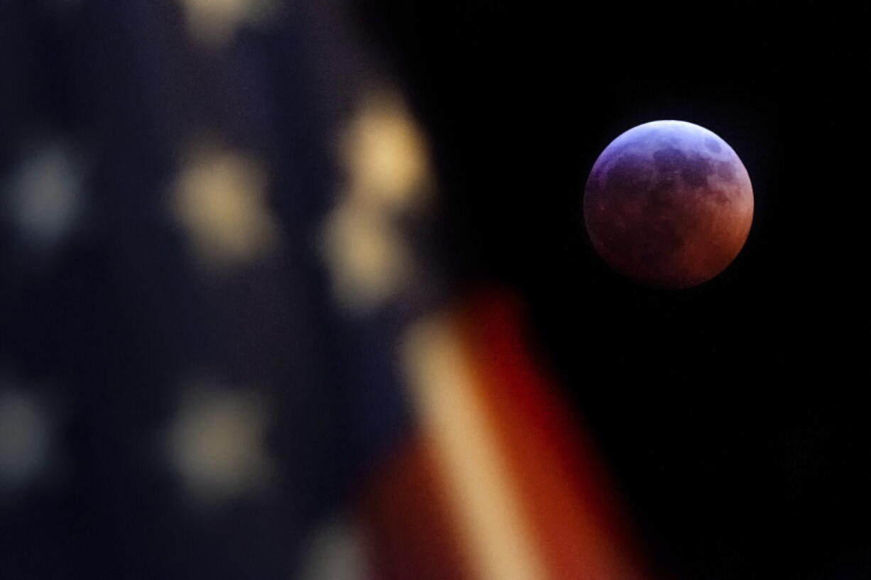 A U.S. Flag in downtown Washington flies in front of the moon during a lunar eclipse, Sunday, Jan. 20, 2019. The entire eclipse will exceed three hours. Totality - when the moon’s completely bathed in Earth’s shadow - will last an hour. Expect the eclipsed, or blood moon, to turn red from sunlight scattering off Earth’s atmosphere. (AP Photo/J.