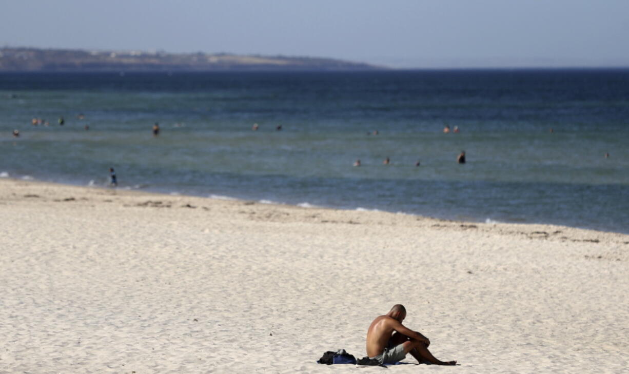 A beachgoer sits in the sun on Glenelg Beach in Adelaide, Australia, Thursday, January 24, 2019. Adelaide sweltered through the highest temperature ever recorded by a major Australian city on Thursday, peaking at a searing 46.6 degrees Celsius (115.9 degrees Fahrenheit) as the drought-parched nation heads toward potentially the hottest January on record.