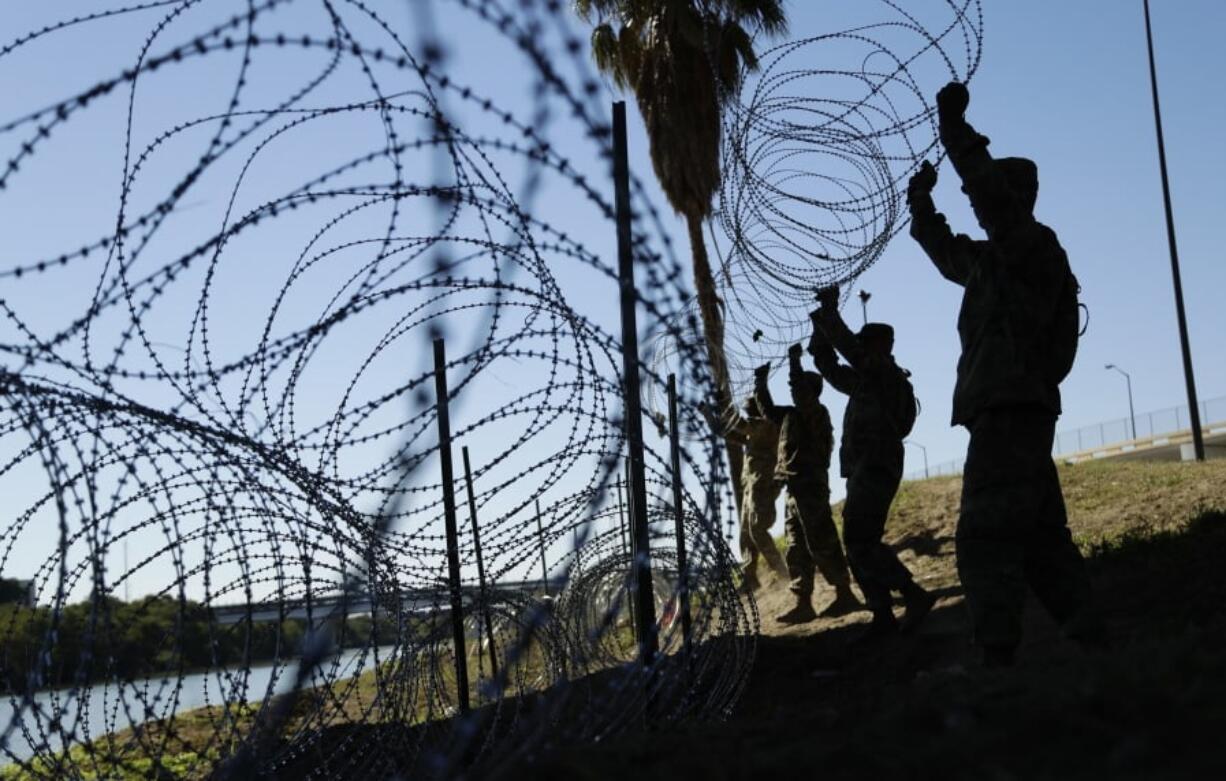 FILE - In this Nov. 16, 2018, file photo, members of the U.S. military install multiple tiers of concertina wire along the banks of the Rio Grande near the Juarez-Lincoln Bridge at the U.S.-Mexico border in Laredo, Texas. Acting Defense Secretary Pat Shanahan says the U.S. will be sending “several thousand” more American troops to the southern border to provide additional support to Homeland Security. He says the troops will mainly be used to install additional wire barriers and provide increased surveillance of the area.