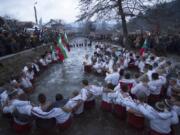 Bulgarians sing and chaindance in the icy waters of the Tundzha river in Kalofer, Bulgaria, Sunday, Jan. 6, 2019. Traditionally, an Eastern Orthodox priest throws a wooden cross in the river and it is believed that the one who retrieves it will be healthy through the year. In the mountain city of Kalofer, in central Bulgaria, dozens of men dressed in white embroidered shirts waded into the frigid Tundzha River waving national flags and singing folk songs.