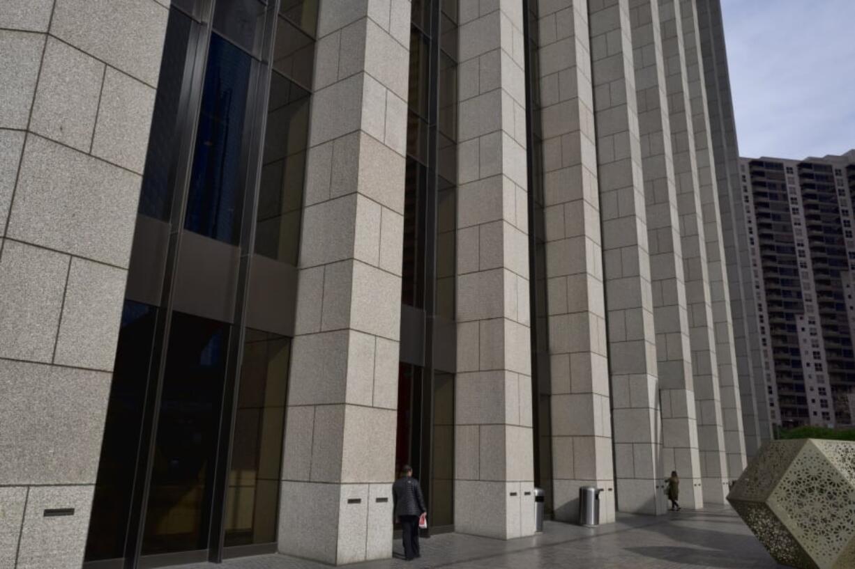 In this Jan. 8, 2019 photo people are towered by the front facade of the Bank of America Plaza Building in downtown Los Angeles. Companies are lining up to tell investors how much they made during the last three months of 2018, and the reports get going in earnest this upcoming week with Citigroup and a slew of other banks on deck. Expectations are high, and Wall Street is forecasting a fifth straight quarter where profit growth topped 10 percent for S&P 500 companies. Bank of America Corp. is expected to report financial earnings next week.