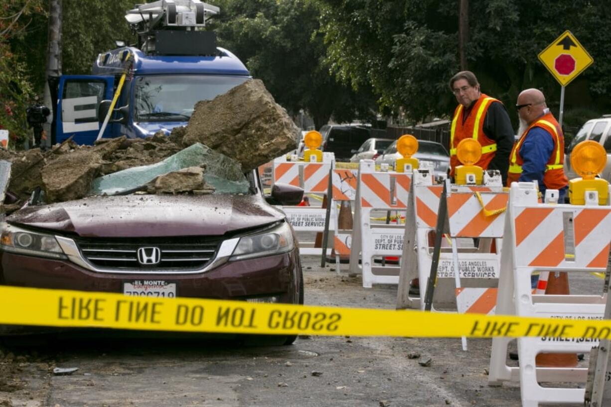 Southern California Gas Company, SoCalGas employees check residential broken gas lines, as a vehicle is buried under mud and concrete slabs as debris slid early morning from beneath a house in Los Angeles, Friday, Jan. 18, 2019. No one was hurt. The three-day drenching put a dent in California’s drought.