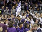 Washington's David Crisp walks in the stands and past fans as he holds up a sign commemorating the men's basketball team winning their 1,000th game on their home court, historic Hec Edmundson Pavilion, in an NCAA college basketball game against California Saturday, Jan. 19, 2019, in Seattle.