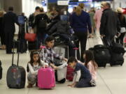 Travelers organize their luggage before entering a security checkpoint Friday at Miami International Airportin Miami. The three-day holiday weekend is likely to bring bigger airport crowds.