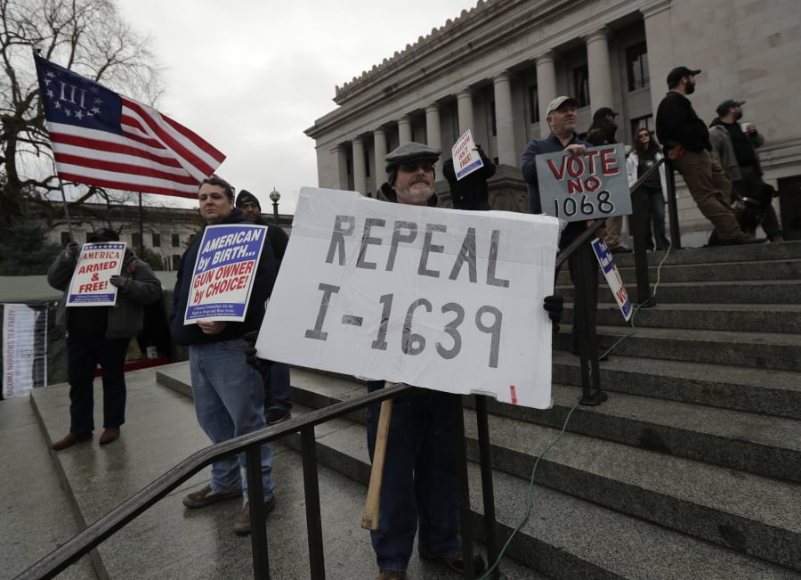 Rick Howell, of Wenatchee, Wash., holds a sign that reads “Repeal I-1639” as he takes part in a gun-rights rally, Friday, Jan. 18, 2019, at the Capitol in Olympia, Wash. Initiative 1639, which was passed by voters in November, 2018, is a package of gun regulations that includes raising the legal age to buy any semi-automatic rifle to 21. (AP Photo/Ted S.