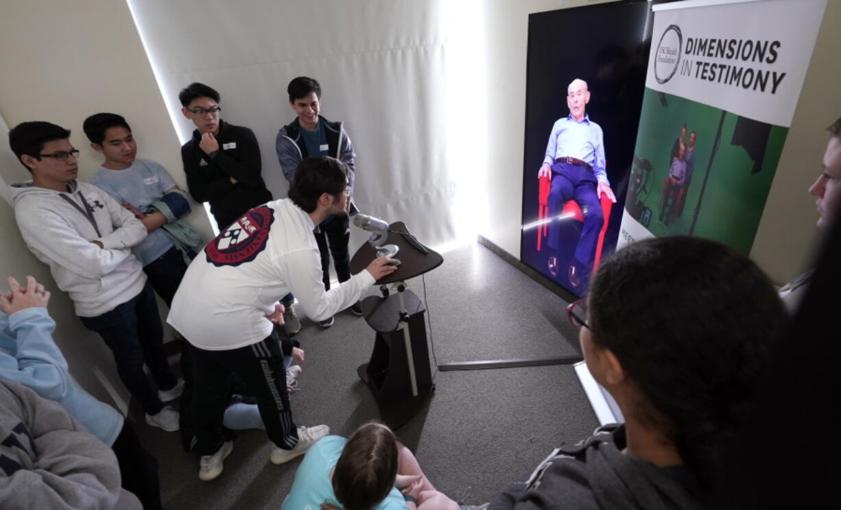 Matthew Rosca-Halmagean, 17, center, a student at Westchester Academy for International Studies, asks a question to Holocaust survivor William Morgan using an interactive virtual conversation exhibit at the the Holocaust Museum Houston Friday, Jan. 11, 2019, in Houston. The University of Southern California Shoah Foundation has recorded 18 interactive testimonies with Holocaust survivors over the last several years. (AP Photo/David J.