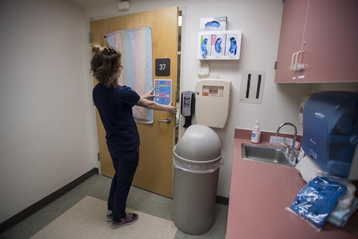 Registered nurse Rebecca Montero holds a sign on the door of the negative pressure airflow room, which is set up to treat patients with the measles or those suspected of having the measles. PeaceHealth and Legacy Health Salmon Creek try to meet potential measles patients outside the hospital for an initial assessment, before masking them and leading them through a private entrance to the airflow room, if they need further assessment.