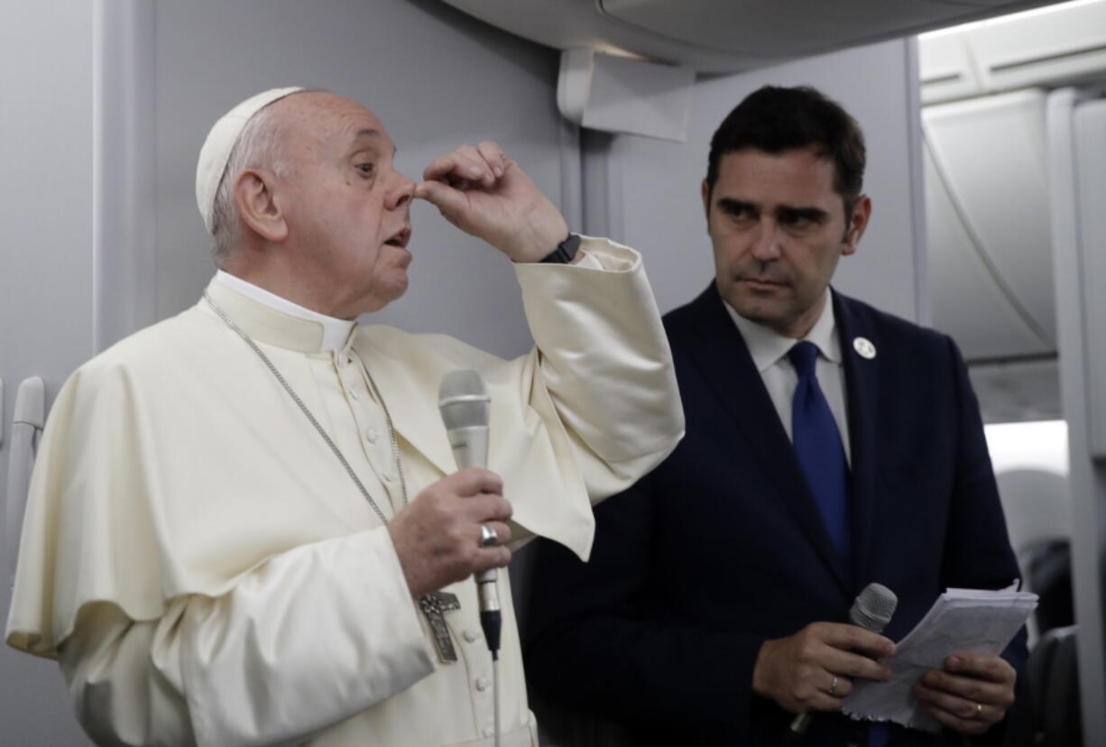 In this picture taken Sunday, Jan. 27, 2019, Pope Francis, flanked by Vatican spokesman Alessandro Gisotti, gestures to describe snobbish, hypocritical Catholics as he answers reporters’ questions aboard the plane after taking off from Panama City.