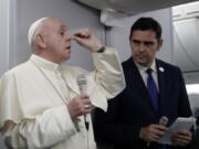 In this picture taken Sunday, Jan. 27, 2019, Pope Francis, flanked by Vatican spokesman Alessandro Gisotti, gestures to describe snobbish, hypocritical Catholics as he answers reporters’ questions aboard the plane after taking off from Panama City.