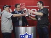 New England Patriots head coach Bill Belichick, left, hands off the championship trophy to quarterback Tom Brady after defeating the Kansas City Chiefs in the AFC Championship NFL football game, Sunday, Jan. 20, 2019, in Kansas City, Mo.