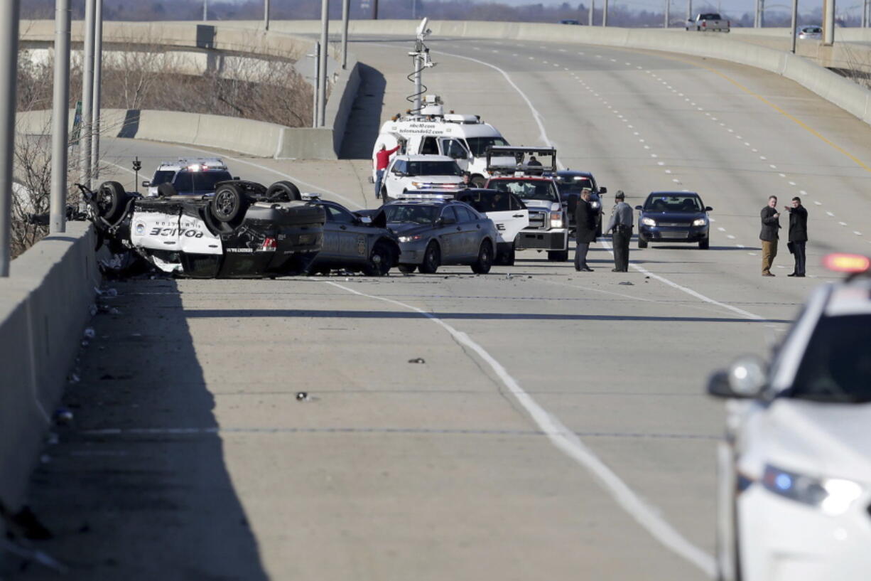 Police work at the scene along Interstate-95 North near the Philadelphia International Airport following a crash during a multi-state police chase Wednesday, Jan. 9, 2019, in Philadelphia. A Wilmington, Del., police vehicle, at left, flipped in the chase. Police launched a manhunt in South Philadelphia for a murder suspect who led police on a chase along Interstate 95, triggering a crash that left three officers injured, and then fled on foot after crashing into a SEPTA bus at Broad and Oregon Streets.