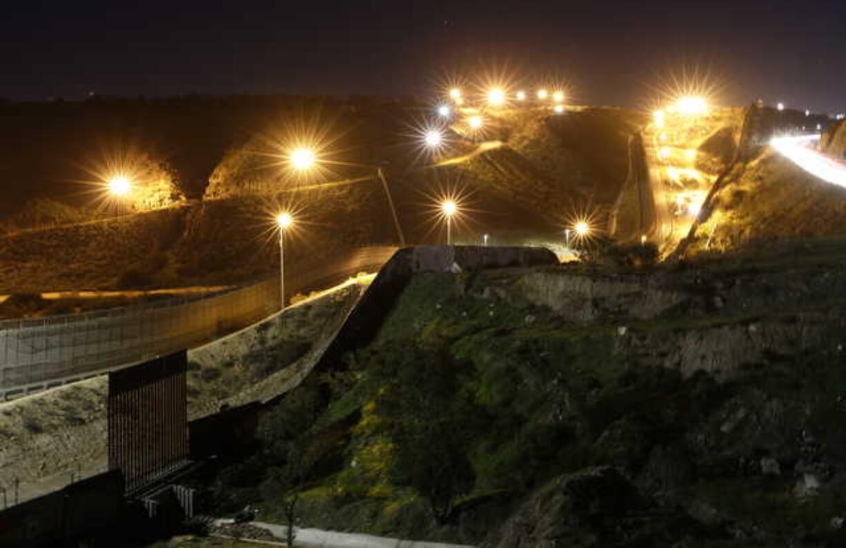 Floodlights from the U.S, illuminate multiple border walls Monday, Jan. 7, 2019, seen from Tijuana, Mexico. With no breakthrough in sight, President Donald Trump will argue his case to the nation Tuesday night that a "crisis" at the U.S.-Mexico border requires the long and invulnerable wall he's demanding before ending the partial government shutdown.