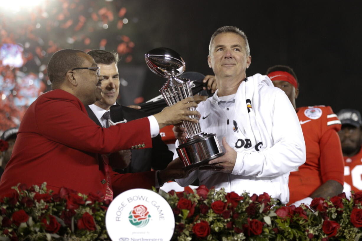 Ohio State coach Urban Meyer, right, holds the trophy after the team's 28-23 win over Washington in the Rose Bowl NCAA college football game Tuesday, Jan. 1, 2019, in Pasadena, Calif. (AP Photo/Jae C.