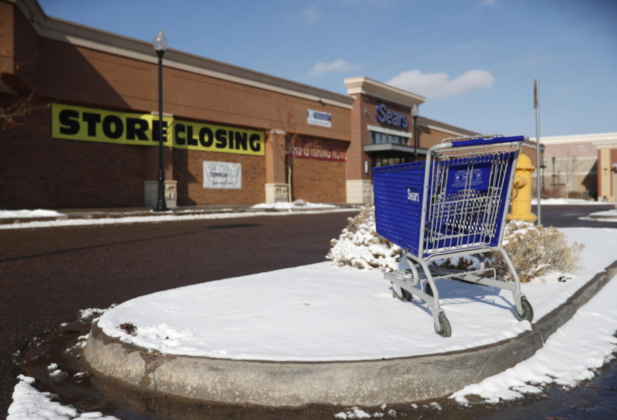 An empty shopping cart sits in the snow on Jan. 1 outside a Sears store in Littleton, Colo.