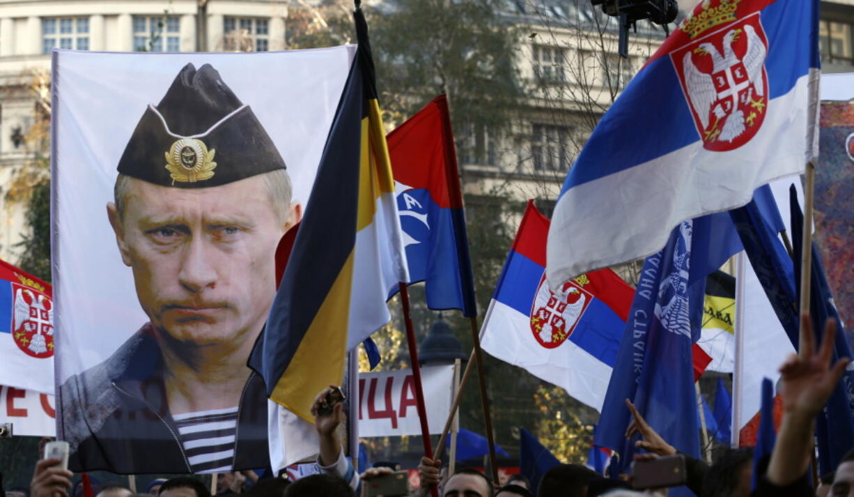 In this Saturday, Nov. 15, 2014 file photo, a supporter of Serbian ultranationalist leader Vojislav Seselj holds a picture of Russian President Vladimir Putin during a protest In Belgrade, Serbia. Vladimir Putin has accused the U.S. and the West of destabilizing the Balkans with NATO expansion policies as Serbia prepares a hero’s welcome for the Russian president.