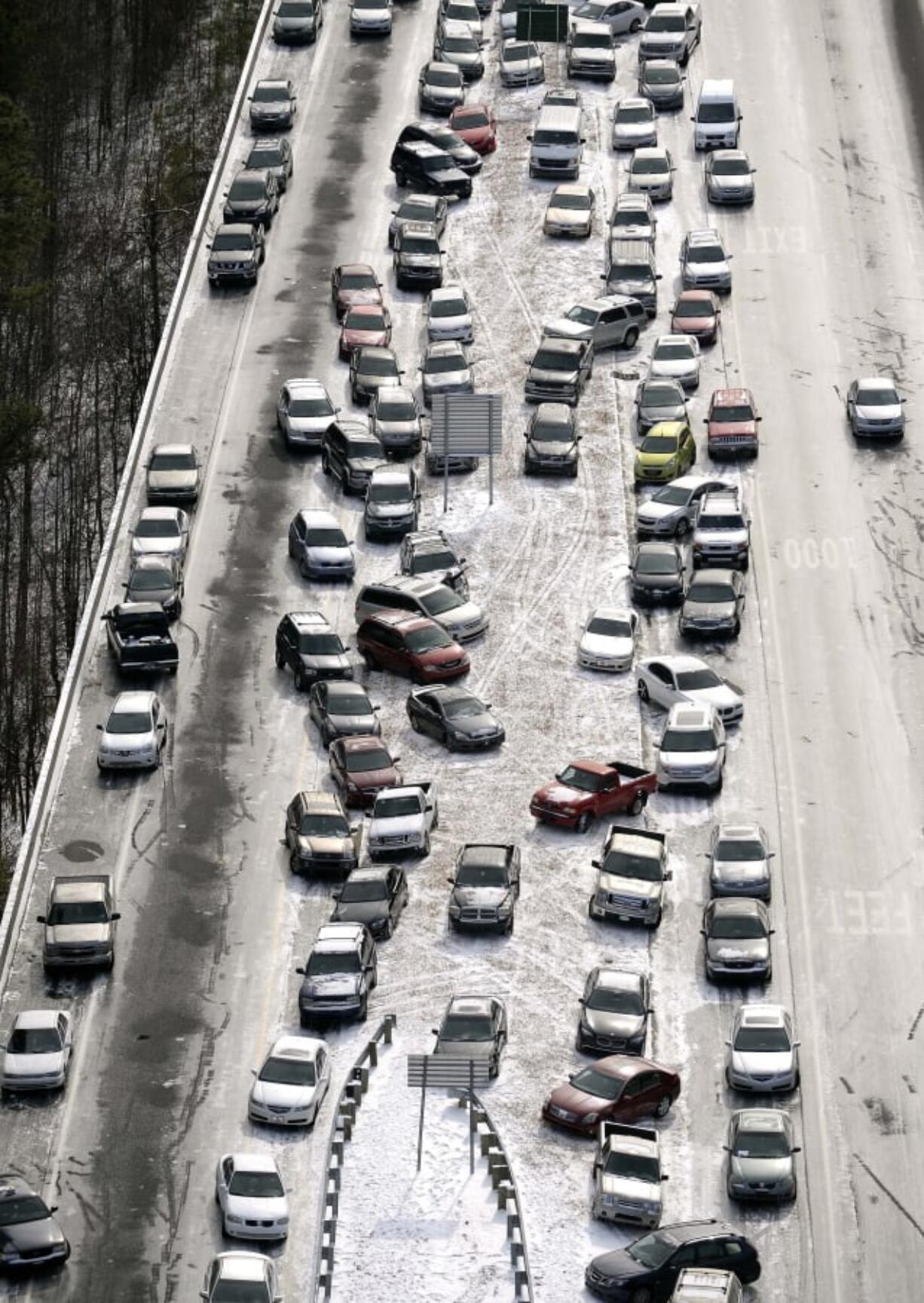 FILE-In this Jan. 29, 2014 aerial file photo, abandoned cars at I-75 headed northbound near the Chattahoochee River overpass are piled up in the median of the ice-covered interstate after a winter snow storm, in Atlanta. A winter storm watch goes into effect at 4 a.m. Tuesday, Jan. 29, for Atlanta, a city known for its ability to grind to a halt even in relatively light snowfalls.