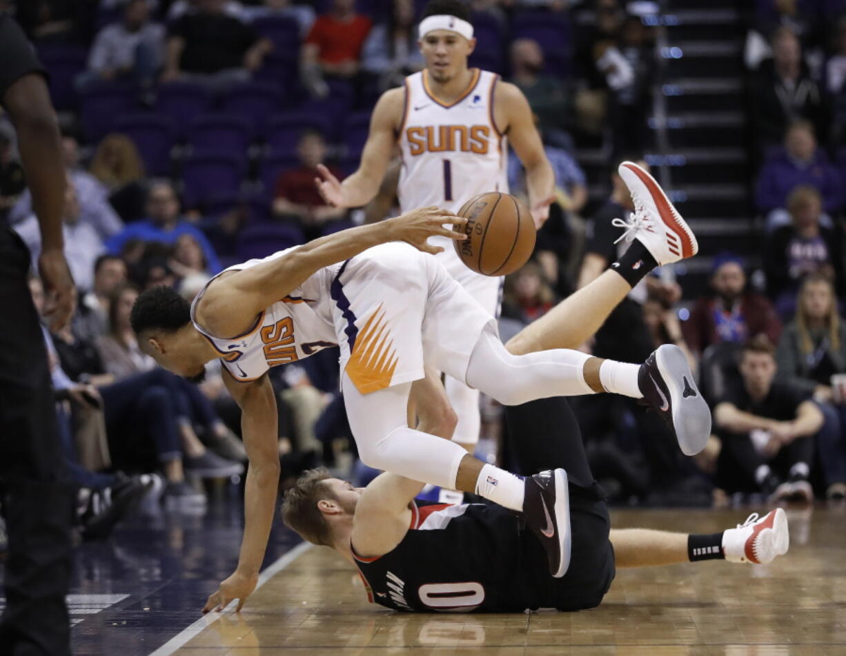 Phoenix Suns guard Elie Okobo, top front, passes around his back after chasing down a loose ball, over Portland Trail Blazers forward Jake Layman during the second half of an NBA basketball game Thursday, Jan. 24, 2019, in Phoenix.