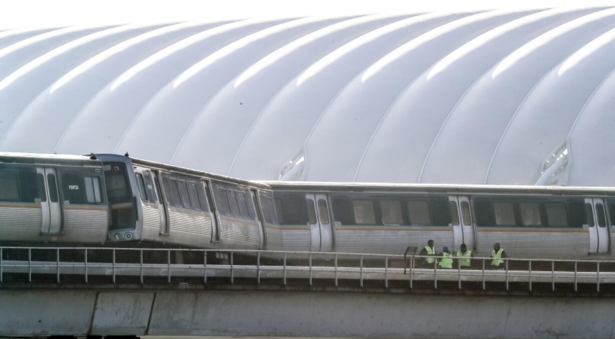 Metropolitan Atlanta Rapid Transit Authority (MARTA) workers look over the tracks after an out-of-service train got stuck just north of Hartsfield-Jackson International Airport, Wednesday, Jan. 16, 2019, in Atlanta. Rail Operations Chief Dave Springstead says normal service to the airport may not resume until Thursday because officials need to bring in a crane to lift the train.