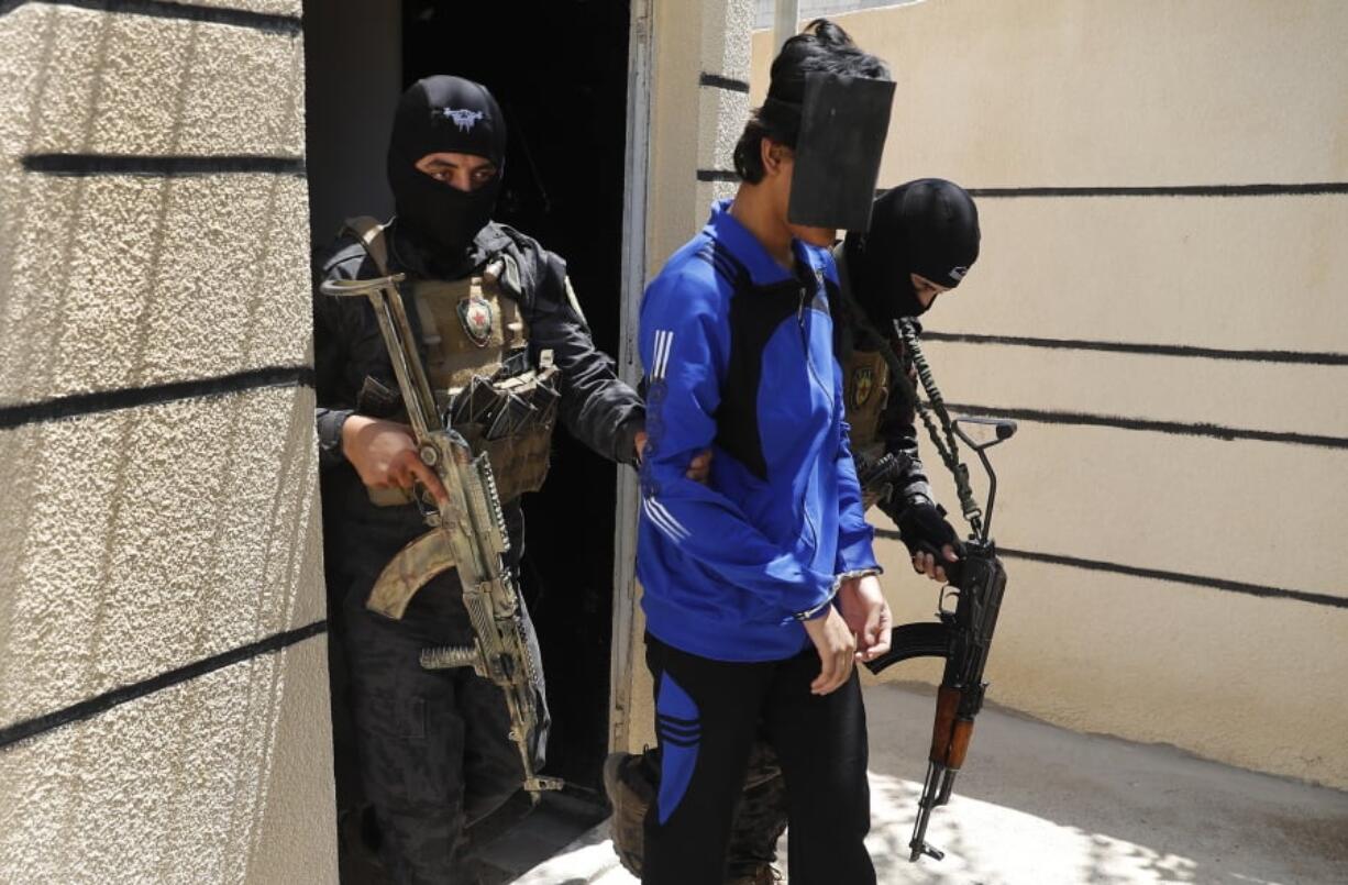 FILE - In this July 21, 2017, file photo, Kurdish soldiers from the Anti-Terrorism Units, carry a blindfolded an Indonesian man suspected of Islamic State membership, at a security center, in Kobani, Syria.