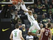 Oregon’s Kenny Wooten, top, dunks over teammate Payton Pritchard, left and Washington State’s Jeff Pollard, right, during the second half of an NCAA college basketball game Sunday, Jan 27, 2019, in Eugene, Ore.