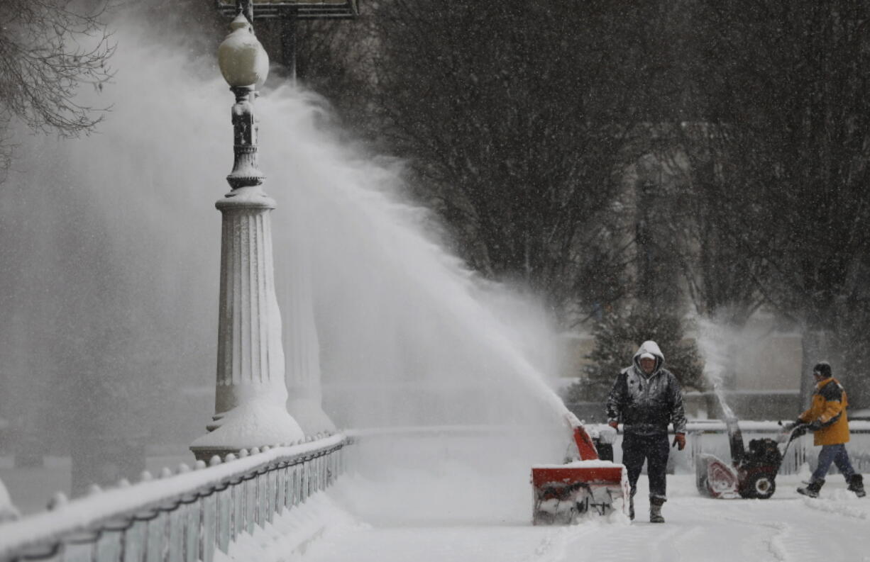 Men clears the snow inside the skating rink in Millennium Park, after a snow storm in Chicago Saturday Jan. 19, 2019.