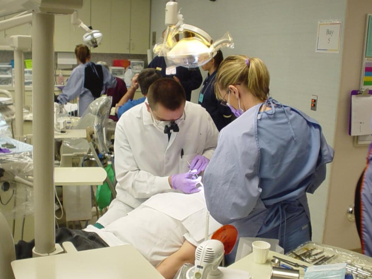 Dentist Karl Rose and a hygienist work on one of 307 children who received free dental care during the second annual Children’s Dental Health Day at Clark College. This year’s event is Saturday.