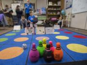 Teacher Mark Sterling, blue vest, and a fourth-grader at Silver Star Elementary School watch as they maneuver a “sphero”, left, in an attempt to knock down stuffed bowling pins while controlling them from across the room. A program levy and technology levy were both passing Tuesday night.