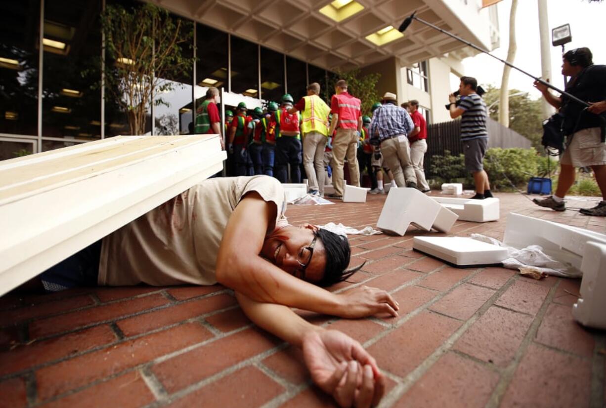 A student lays on the ground simulating injuries sustained in an earthquake as media follow members of USC’s Campus Emergency Response Team during a drill on October 15, 2015, in Los Angeles.