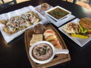 The salmon dip, clockwise from front, the Bleu Dirties, chicken and veggie wild rice soup, and the bison bacon and cheddar burger are pictured at Ben’s Bottle Shop.